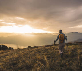 Ältere Frau mit Wanderstöcken beim Wandern auf einem Berg - UUF28178