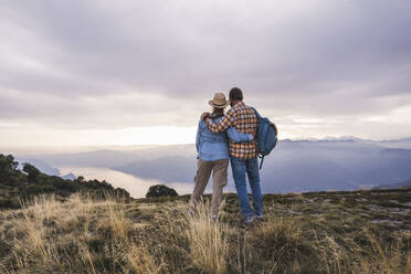 Loving couple standing with arms crossed on mountain - UUF28204