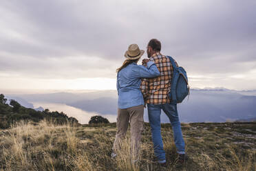 Couple standing together on mountain at sunset - UUF28205