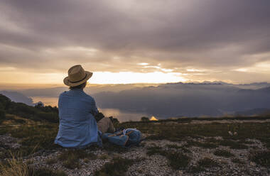 Mature woman wearing hat sitting on mountain - UUF28207