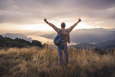 Carefree man standing with arms raised on mountain - UUF28217