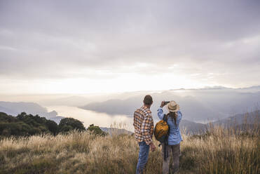 Mature man with woman photographing through smart phone - UUF28218