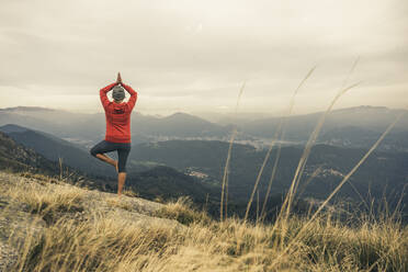 Mature woman practicing tree pose yoga on mountain - UUF28223