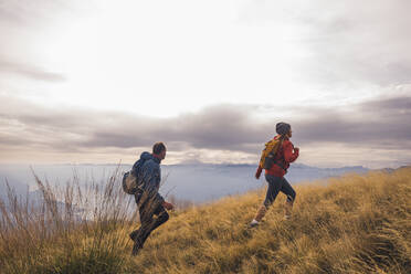 Mature man and woman with backpack hiking on mountain - UUF28242