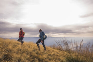 Man and woman with backpacks hiking on mountain - UUF28243