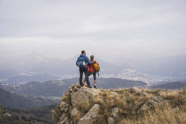 Mature man and woman standing with backpack on rock - UUF28245