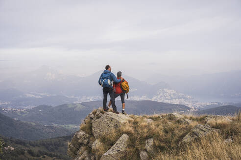 Älterer Mann und Frau stehen mit Rucksack auf einem Felsen - UUF28245