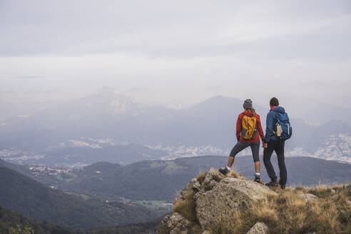 Älterer Mann und Frau halten sich an den Händen und stehen auf einem Felsen - UUF28246