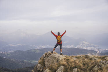 Carefree mature woman standing with arms raised on rock - UUF28248