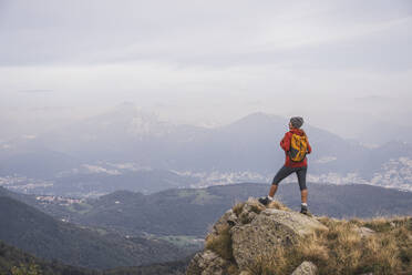 Reife Frau mit Rucksack auf einem Felsen stehend - UUF28250