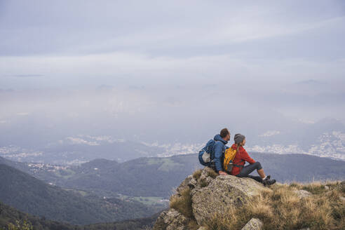 Älterer Mann und Frau sitzen auf einem Felsen - UUF28251