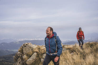 Smiling man and woman hiking on mountain - UUF28253