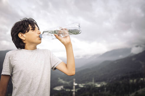 Durstiger Junge trinkt Wasser aus einer Flasche - ANAF00980