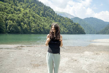 Smiling woman standing in front of lake - ANAF00990