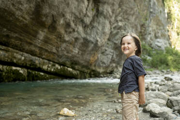 Glücklicher Junge am Flussufer im Urlaub - ANAF00992
