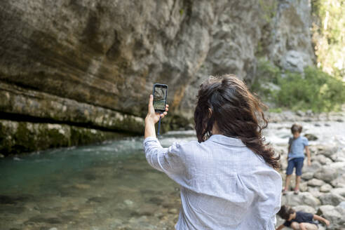 Frau fotografiert im Urlaub die Natur mit ihrem Smartphone - ANAF00994