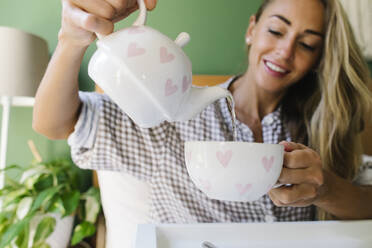 Woman pouring hot water into cup at home - TYF00708