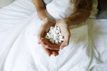 Hands of woman holding pills in bed at home - TYF00725