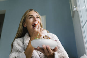 Woman eating strawberry at home - TYF00733