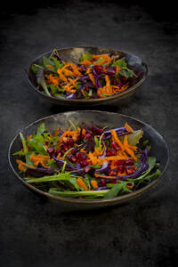 Studioaufnahme von zwei Tellern mit verzehrfertigem veganem Salat vor schwarzem Hintergrund - LVF09276
