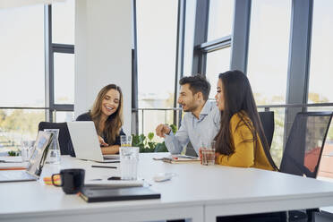 Businessman discussing with colleagues at desk in office - BSZF02049