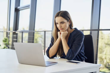 Geschäftsfrau beobachtet Laptop am Schreibtisch im Büro sitzend - BSZF02085