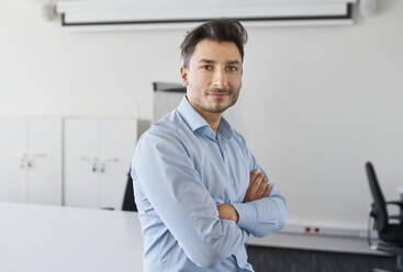 Confident businessman with arms crossed at office - BSZF02106