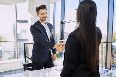 Smiling recruiter doing handshake with candidate after interview at office - BSZF02128