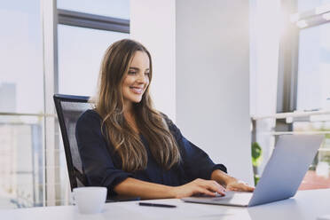 Confident business woman sitting at desk stock photo (135604