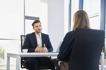 Personalvermittler im Gespräch mit einem auf einem Stuhl sitzenden Bewerber im Büro - BSZF02142