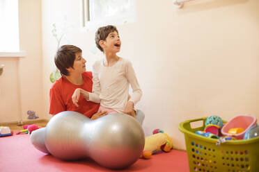 Physiotherapeutin und Mädchen mit Behinderung spielen im Rehabilitationszentrum - OSF01386