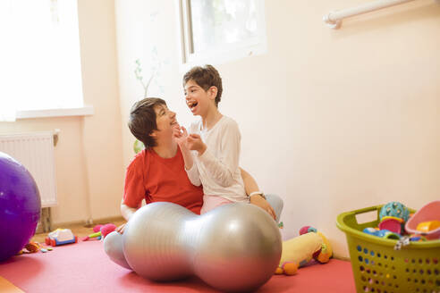 Glückliche Physiotherapeutin und Mädchen mit Behinderung im Rehabilitationszentrum - OSF01387