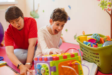 Happy physical therapist and girl with disability playing at rehabilitation centre - OSF01388