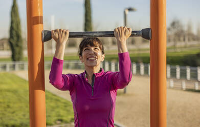 Glückliche Frau beim Training mit Reck im Park - JCCMF09345