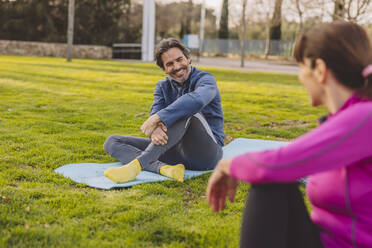 Happy mature man and woman sitting in park - JCCMF09354