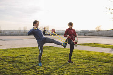 Mature man and woman practicing exercise in park - JCCMF09370