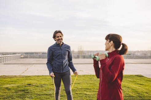 Glücklicher Mann beim Sport mit Frau im Park an einem sonnigen Tag - JCCMF09376