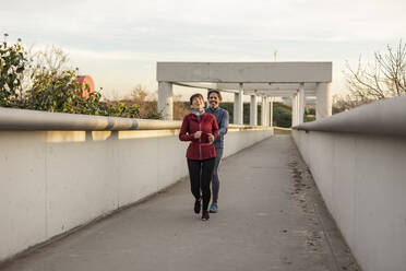 Glücklicher reifer Mann und Frau laufen und genießen auf Brücke - JCCMF09395