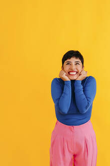 Excited woman with pixie cut against yellow background - TCEF02230