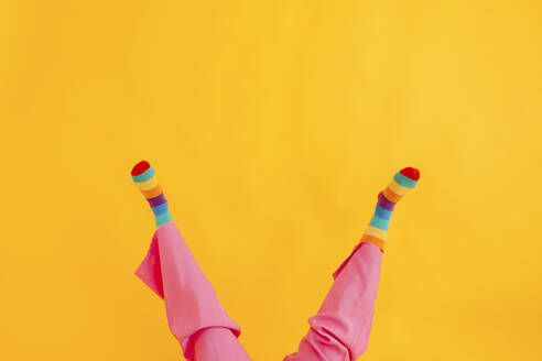 Füße einer Frau mit mehrfarbigen Socken vor gelbem Hintergrund - TCEF02262