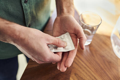 Man taking pill from blister pack, close up - BSZF02174