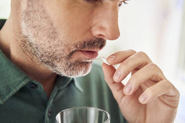 Close-up of adult man taking pill - BSZF02175