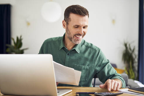 Contented man doing paperwork calculating finaces - BSZF02202