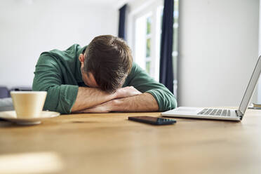 Überarbeiteter Mann schläft auf den Armen am Schreibtisch - BSZF02234
