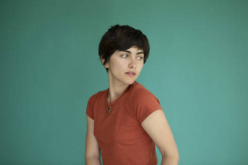 Young woman with short hair against green background - AXHF00253