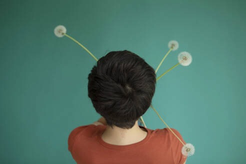 Woman holding dandelions facing green background - AXHF00256