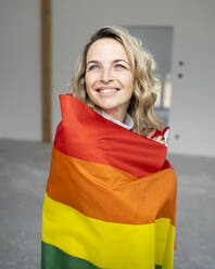Glückliche Frau, eingewickelt in eine mehrfarbige Flagge - HMEF01512