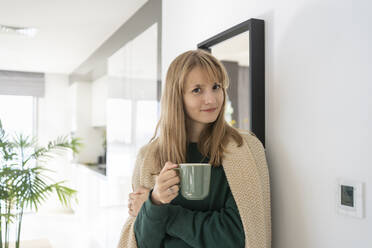 Lächelnde Frau stehend mit Teetasse zu Hause - SVKF01234