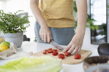 Frau schneidet Kirschtomaten zu Hause - SVKF01255