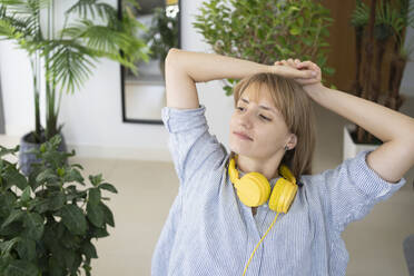 Thoughtful woman with headphones sitting at home - SVKF01274